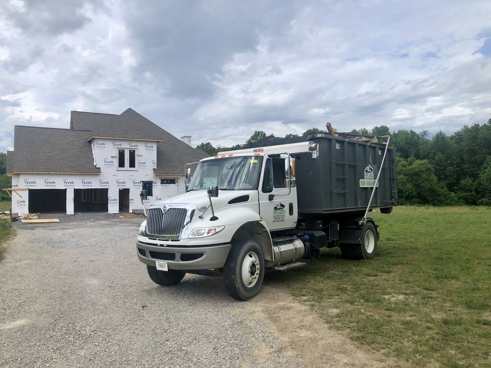 Reliable Dumpster Rental truck delivering a dumpster to a new home construction site